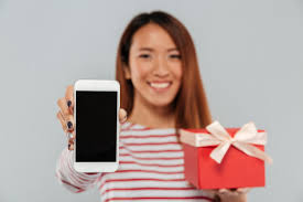Free Photo | Happy young asian woman showing display of phone holding gift.